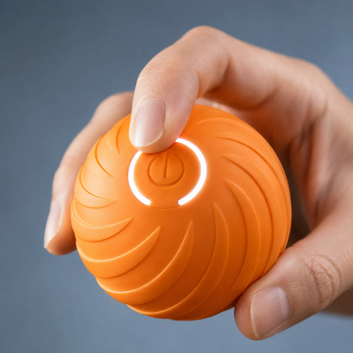 Un index appuie sur le bouton circulaire lumineux de la balle motorisée orange